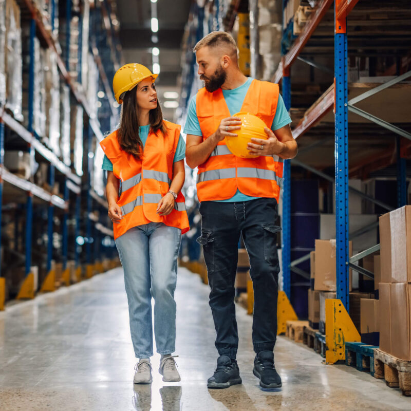 Two warehouse employees, walking and talking.